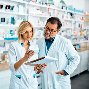 Berufshaftpflichtversicherung: Unverzichtbarer Schutz bei Arzneimittelabgabe Apotheker bespricht mit Kollegin in der Apotheke.