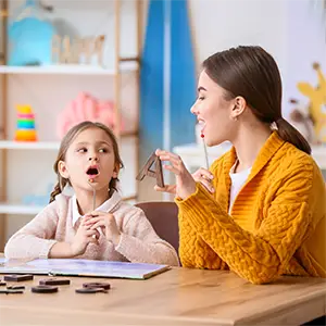 Logopäden bei Sprachübung mit einem Mädchen
