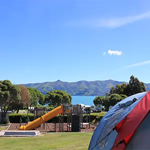 Spielplatz mit Rutsche und Blick auf den See mit Zelt im Vordergrund