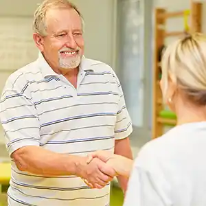 eine Phyiotherapeutin begrüßt einen Patienten