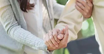 Pflegerin hält die Hand einer alten Dame