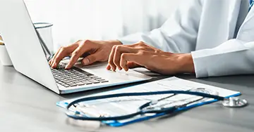 Hausärztin aktualisiert die Patientenakte am Laptop