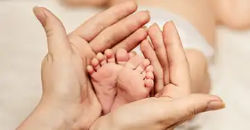 Hände halten Füße eines Babys