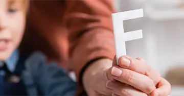 Logopädin fält einen Buchstaben in der Hand