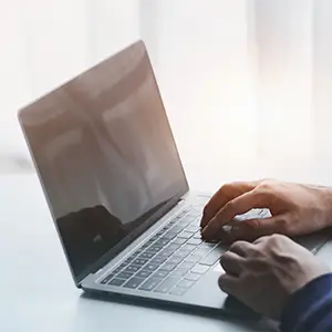 Eine Optiker tippt auf einem Laptop auf einem weißen Tisch.