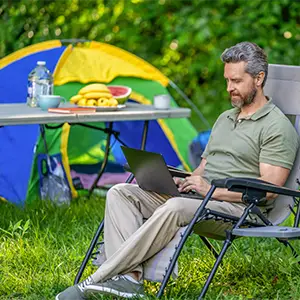 Mann arbeitet am Laptop beim Camping in der Natur