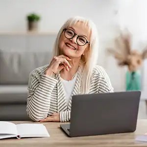 eine Frau sitzt vor dem Computer und blickt lächelnd in die Kamera