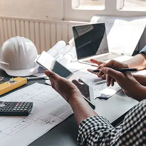 Architekt am Schreibtisch mit Tablet und Bauplänen