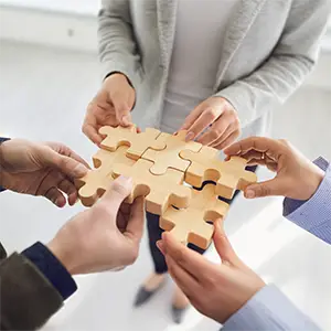 Hände setzen ein Holzpuzzle zusammen