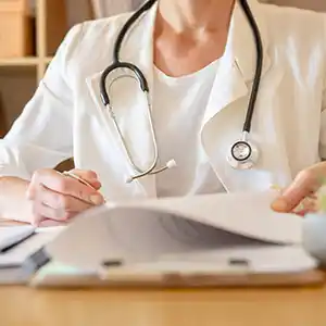 Therapeutin sitzt am Schreibtisch und liest in Unterlagen