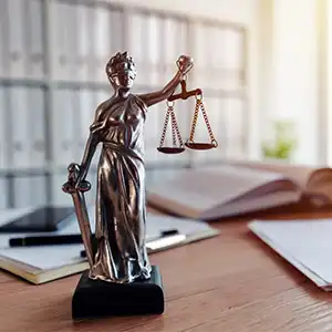 Schreibtisch im Büro eines Anwalt mit Fokus auf einer Figur von Justitia